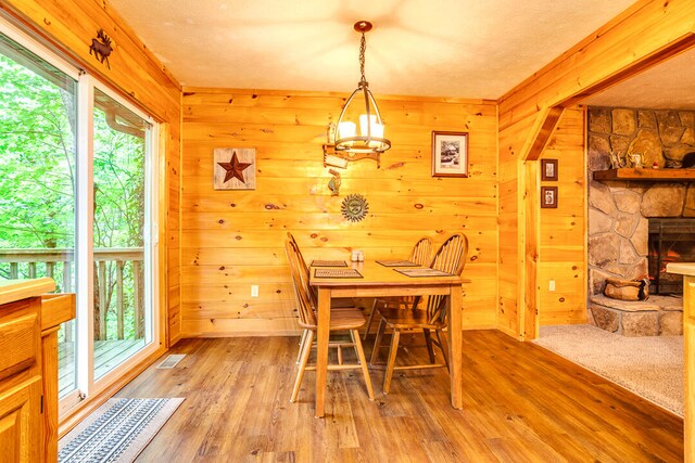 dining space with light wood-type flooring, a fireplace, and wooden walls