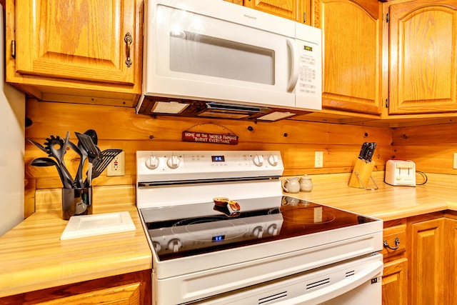 kitchen with white appliances and wood walls