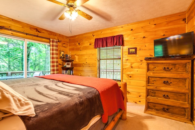 carpeted bedroom featuring ceiling fan, wood walls, and a textured ceiling