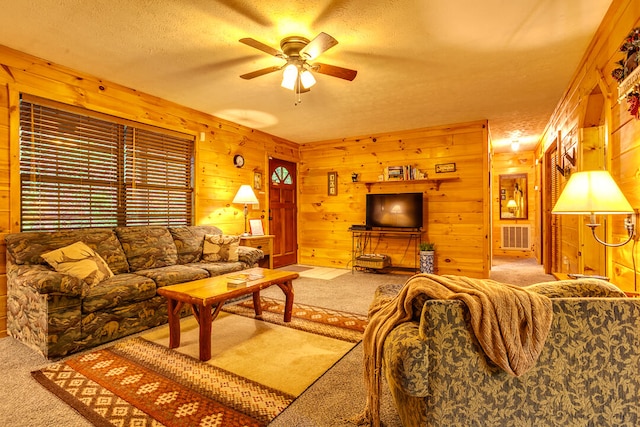 living room with carpet, a textured ceiling, ceiling fan, and wooden walls