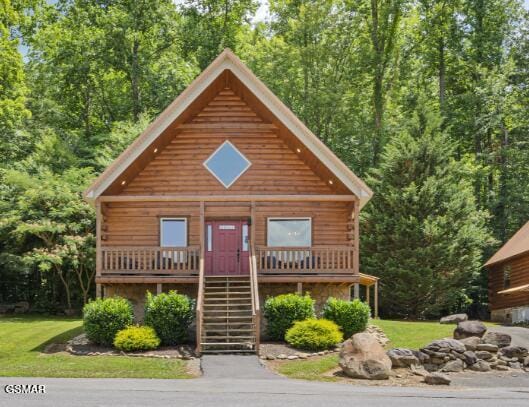 cabin with stone siding, covered porch, a front lawn, and stairs