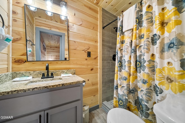 bathroom featuring a shower with curtain, wooden walls, vanity, and toilet