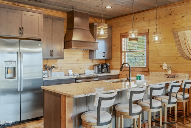 kitchen featuring light stone countertops, appliances with stainless steel finishes, custom exhaust hood, wooden ceiling, and hanging light fixtures