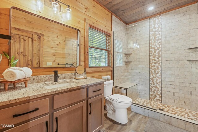 bathroom featuring hardwood / wood-style flooring, toilet, a tile shower, and wooden walls