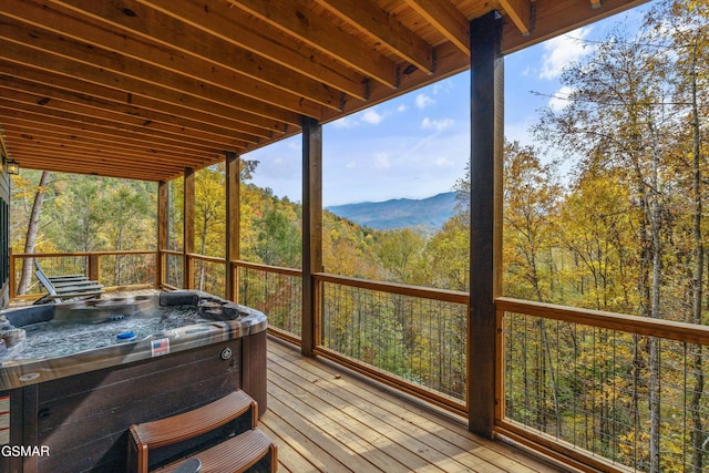 sunroom with a mountain view, a hot tub, and a wealth of natural light