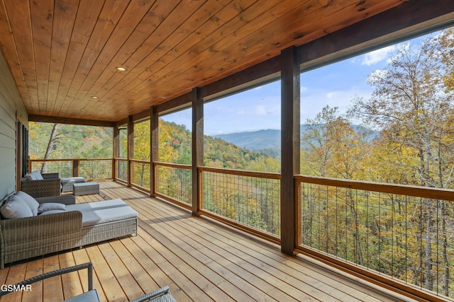 sunroom with a mountain view, a healthy amount of sunlight, and wooden ceiling