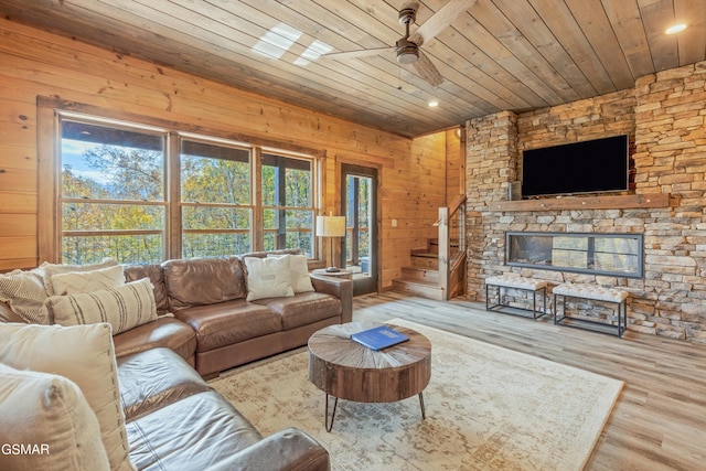 living room featuring ceiling fan, wood-type flooring, wooden ceiling, and wooden walls