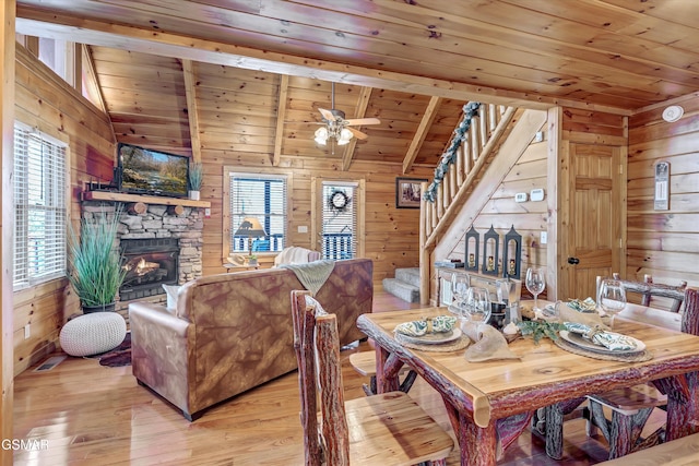 dining space featuring vaulted ceiling with beams, wooden ceiling, wood walls, and stairs