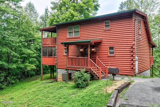 cabin with central AC, a front lawn, and a balcony