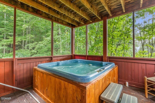 unfurnished sunroom with a hot tub and a forest view