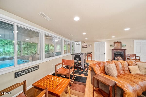 living room with a warm lit fireplace, baseboards, visible vents, and recessed lighting