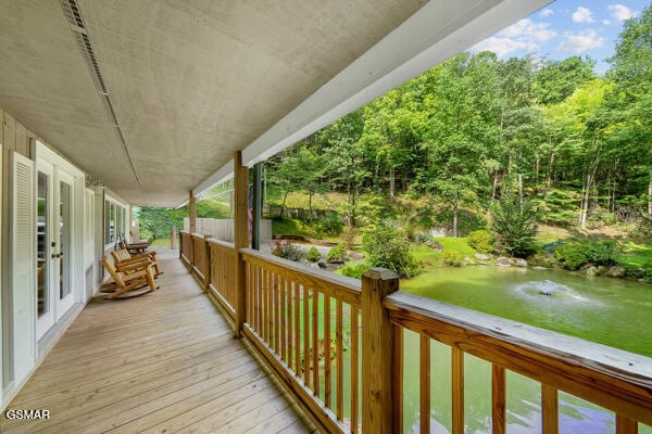 deck with a water view and a lawn