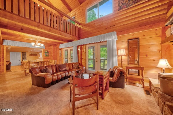 living room featuring french doors, an inviting chandelier, wood ceiling, wooden walls, and beamed ceiling