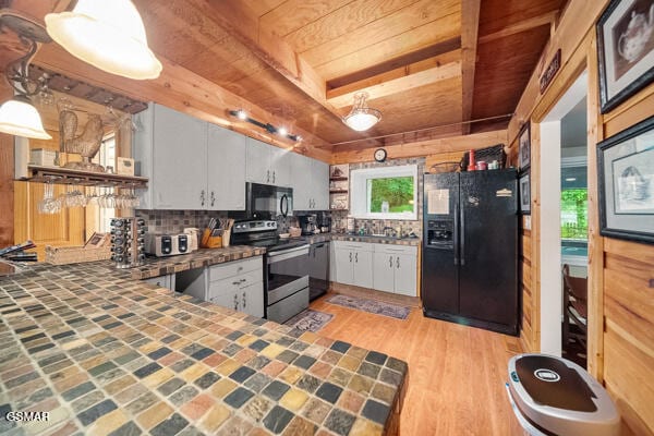 kitchen with pendant lighting, decorative backsplash, white cabinetry, a peninsula, and black appliances