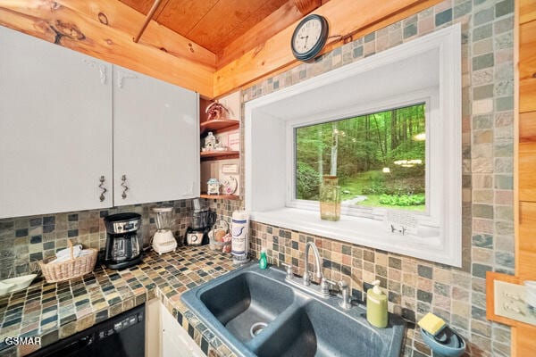 kitchen featuring white cabinets, dishwasher, a sink, open shelves, and backsplash