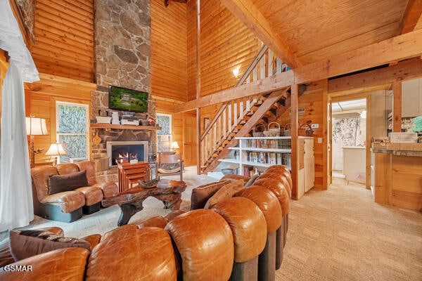 living area with a stone fireplace, stairway, wooden ceiling, and wooden walls