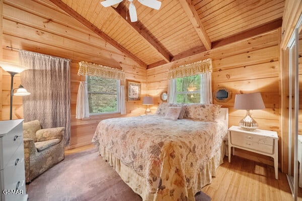 bedroom featuring vaulted ceiling with beams, wood walls, wood ceiling, and multiple windows