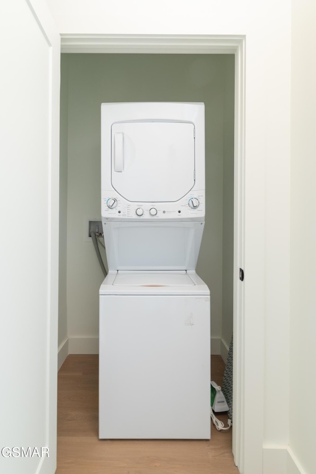 clothes washing area featuring light hardwood / wood-style flooring and stacked washer and clothes dryer