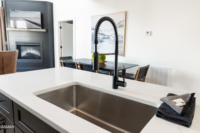 kitchen with a fireplace, sink, and light stone countertops