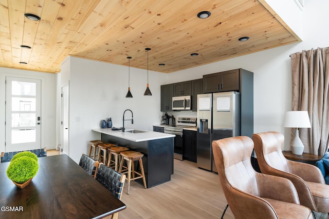 kitchen featuring kitchen peninsula, stainless steel appliances, sink, a breakfast bar area, and pendant lighting