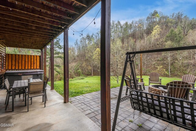 view of patio / terrace featuring an outdoor fire pit, a wooded view, and outdoor dining space
