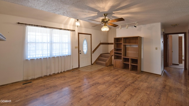 entryway featuring ceiling fan, track lighting, hardwood / wood-style floors, and a textured ceiling