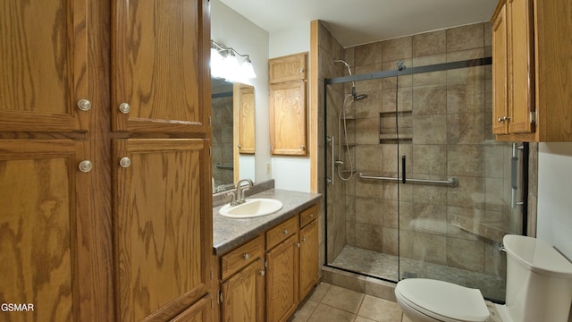 bathroom with tile patterned flooring, vanity, an enclosed shower, and toilet