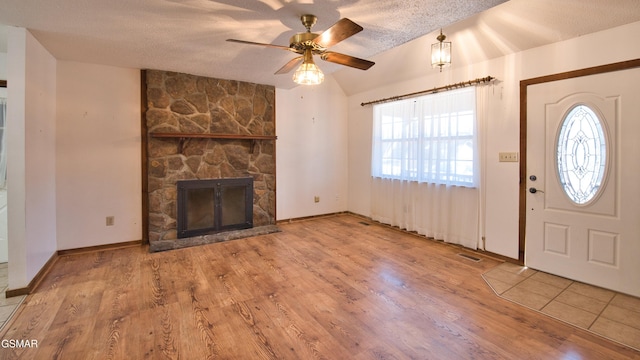 foyer entrance featuring lofted ceiling, a textured ceiling, ceiling fan, a fireplace, and light hardwood / wood-style floors