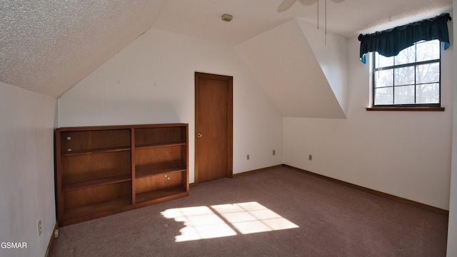 bonus room featuring ceiling fan, carpet flooring, vaulted ceiling, and a textured ceiling