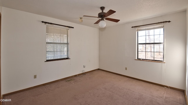 empty room with ceiling fan, light colored carpet, and a textured ceiling