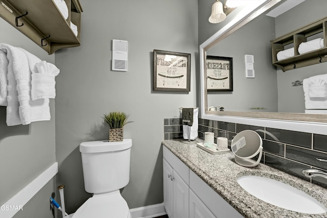 bathroom featuring toilet, tasteful backsplash, and vanity