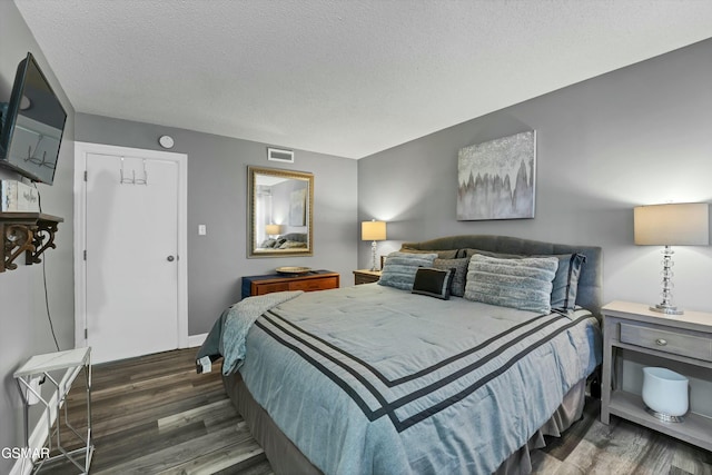 bedroom with a closet, dark hardwood / wood-style flooring, and a textured ceiling