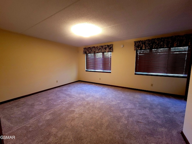 carpeted empty room featuring a textured ceiling