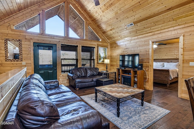 living room with a ceiling fan, visible vents, and wood walls