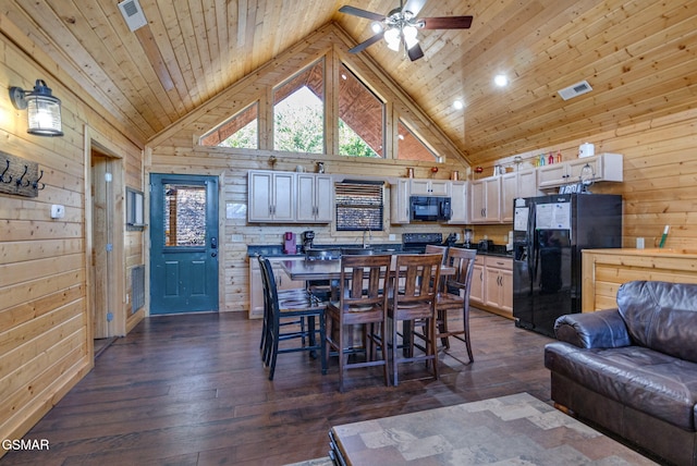 dining area featuring dark wood-style flooring, visible vents, and wooden walls