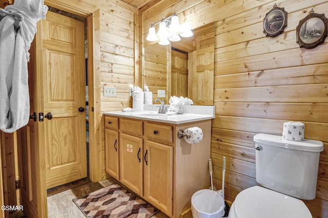 bathroom featuring vanity, toilet, and wooden walls