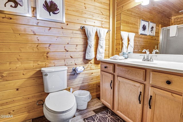 full bathroom featuring toilet, wood walls, a shower with shower door, and vanity