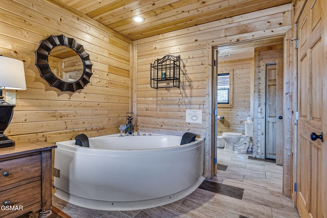 bathroom with wooden walls, toilet, wooden ceiling, wood finished floors, and a garden tub