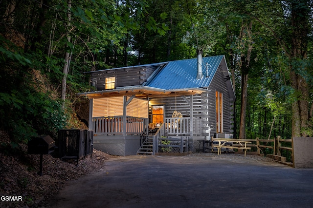 rustic home with a porch, fence, and metal roof
