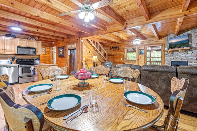 dining space featuring a fireplace, beam ceiling, wooden walls, and wood ceiling