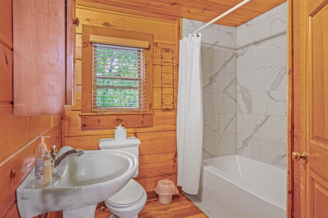 full bathroom with sink, wood walls, toilet, wood ceiling, and shower / tub combo