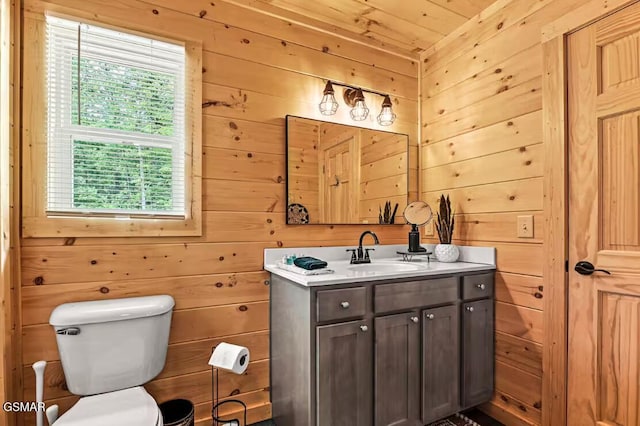 bathroom with wood walls, vanity, a healthy amount of sunlight, and toilet