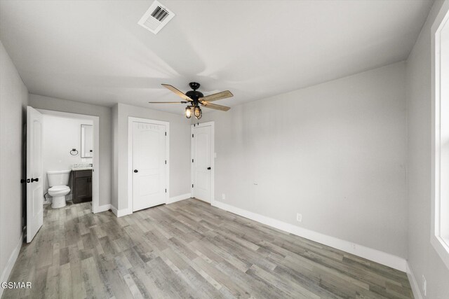 unfurnished bedroom with ceiling fan, light wood-type flooring, and connected bathroom