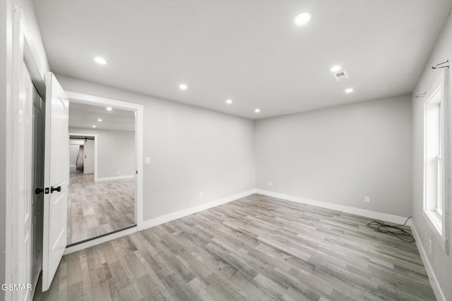 empty room with a barn door and light wood-type flooring