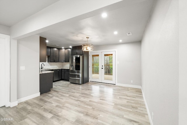 kitchen with french doors, hanging light fixtures, light hardwood / wood-style flooring, stainless steel refrigerator with ice dispenser, and backsplash