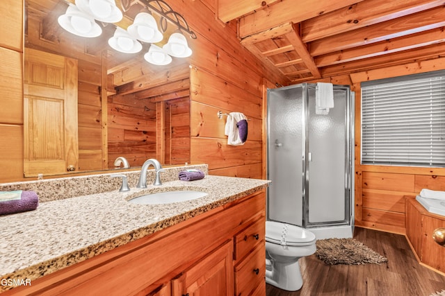 bathroom with wooden walls, a shower stall, wood finished floors, vanity, and toilet