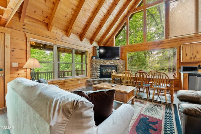 living room with wood finished floors, wooden walls, high vaulted ceiling, wooden ceiling, and a stone fireplace