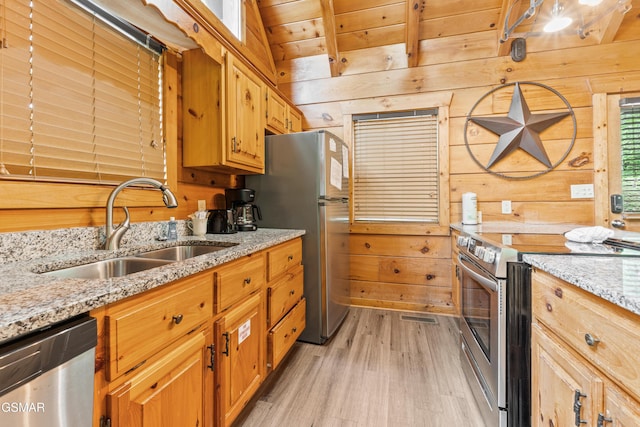 kitchen featuring stainless steel appliances, wooden walls, wood ceiling, a sink, and light wood-style floors