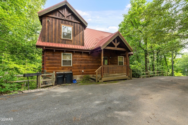 rustic home featuring metal roof and fence