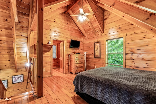 bedroom with beam ceiling, wooden walls, light wood-style flooring, and high vaulted ceiling